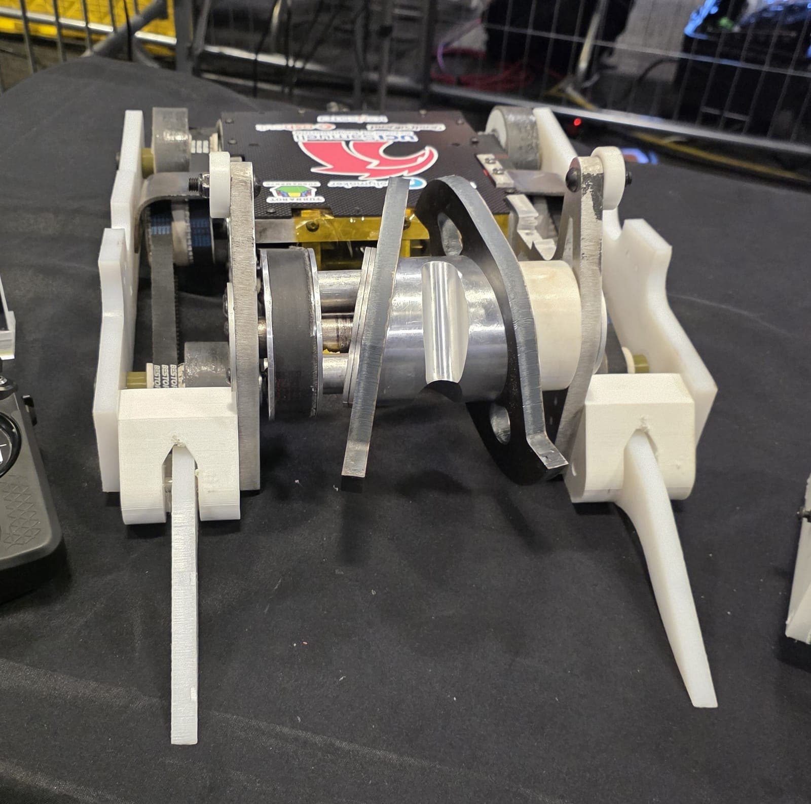 Shear Force on the pit table at Open Sauce 2026: white armor, cast grey wheels and the angled weapon disc
